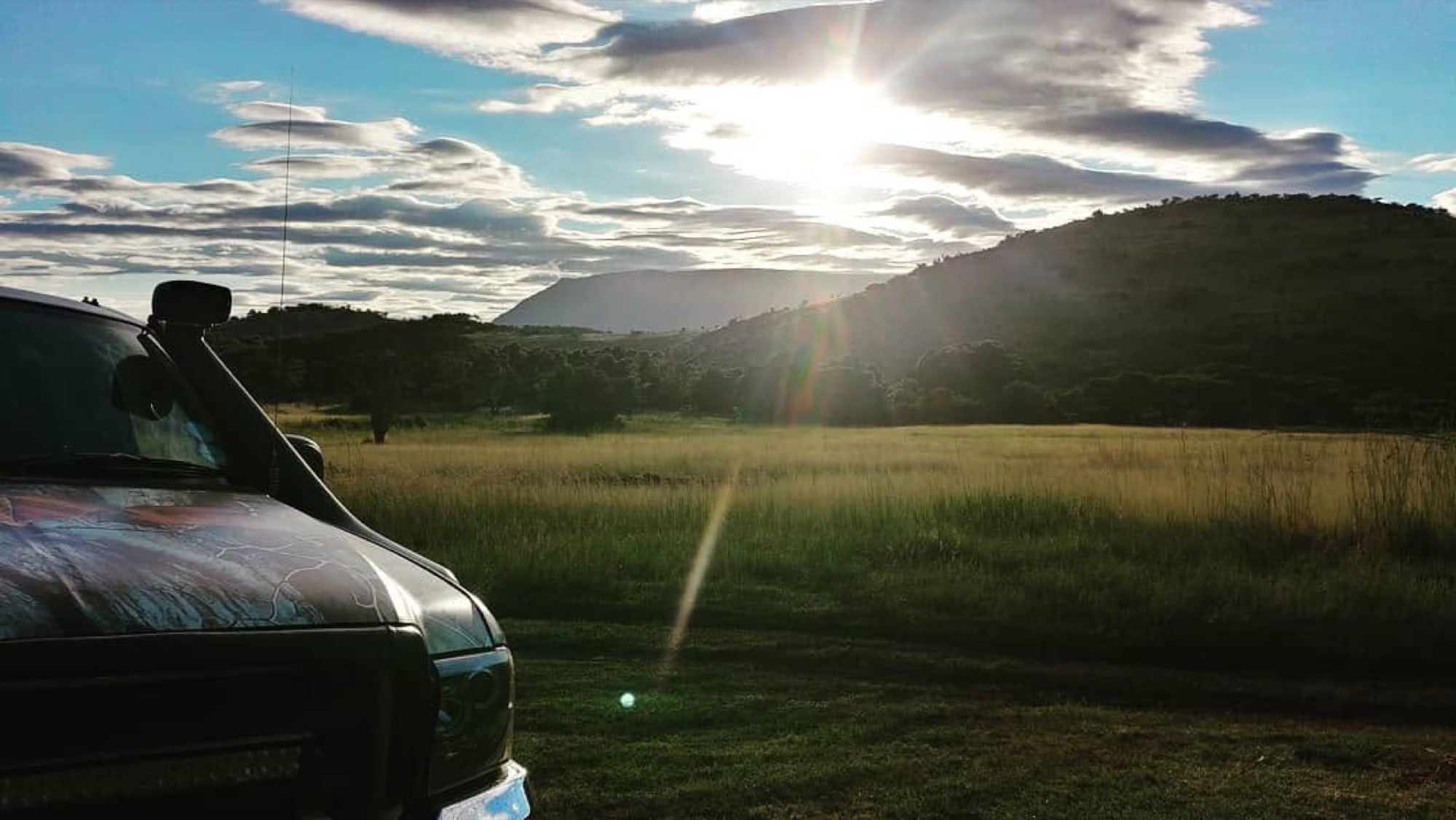 Safari bakkie at first light, hills and open grass ahead