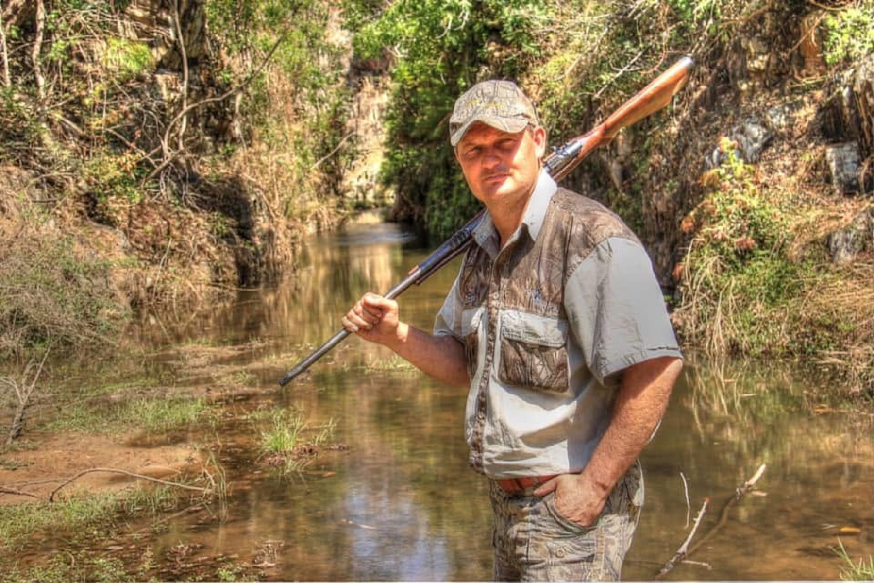 Izak Kirsten with a rifle on a river in the bush